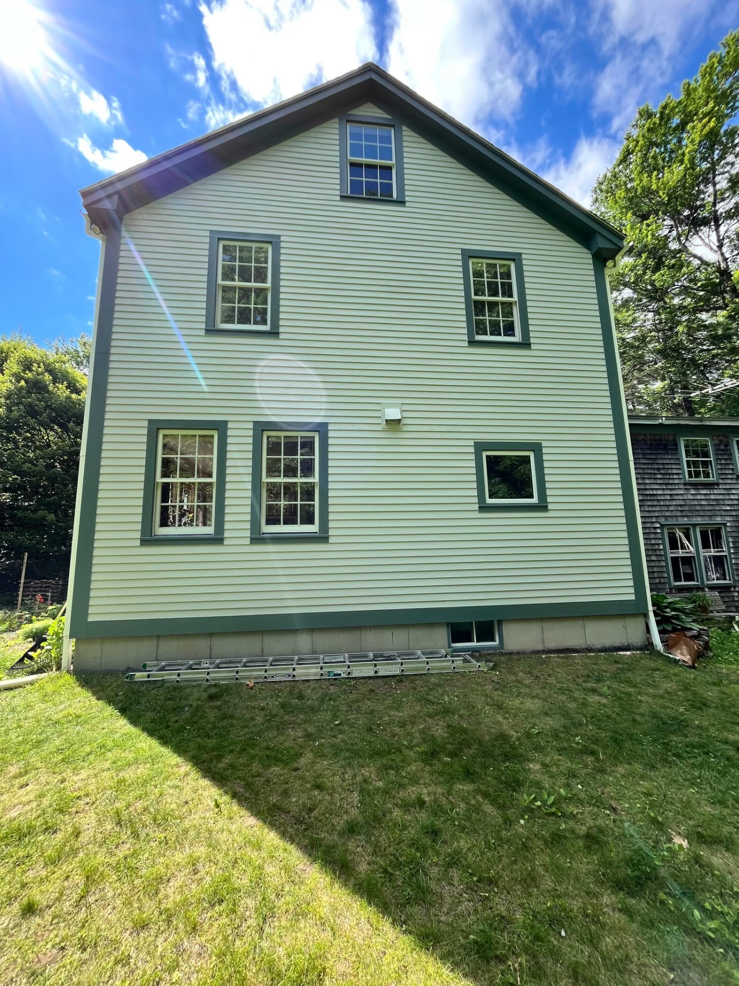 New England colonial home after a full exterior repaint in soft green with deeper green trim