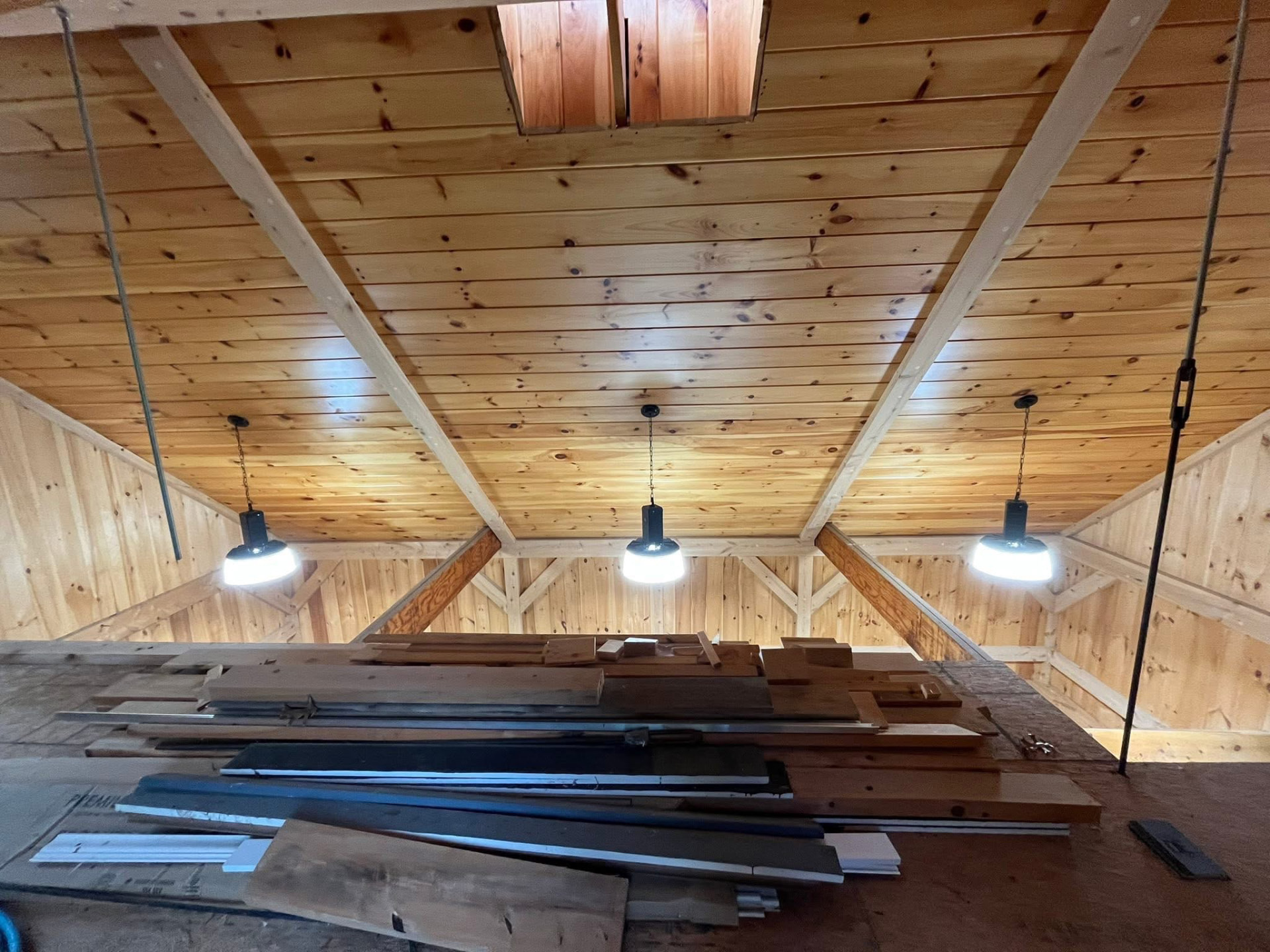 Sealed pine plank ceiling with beams and pendant lighting in a finished barn loft