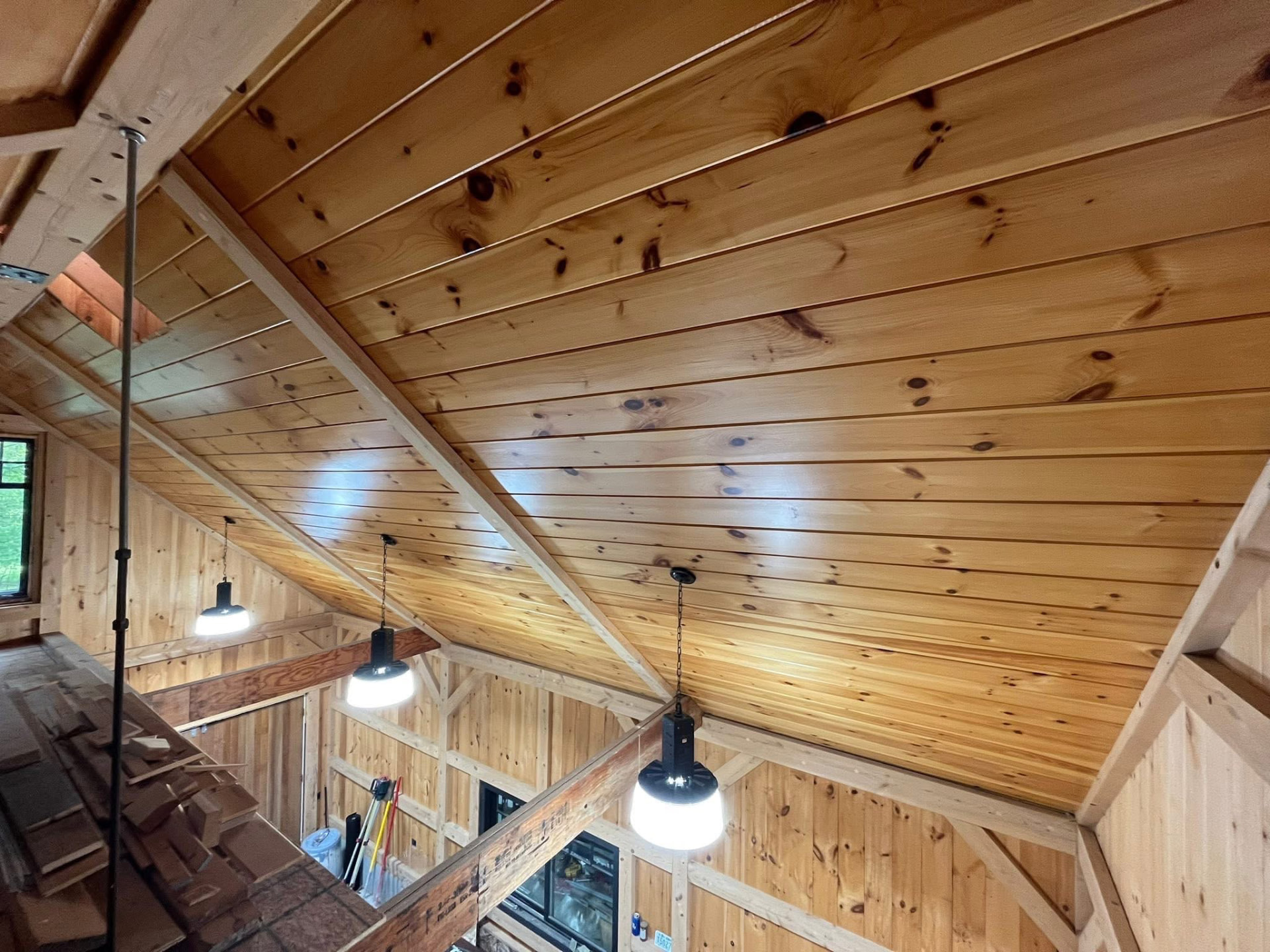 Clear-coated knotty pine ceiling boards and beams in a finished timber loft