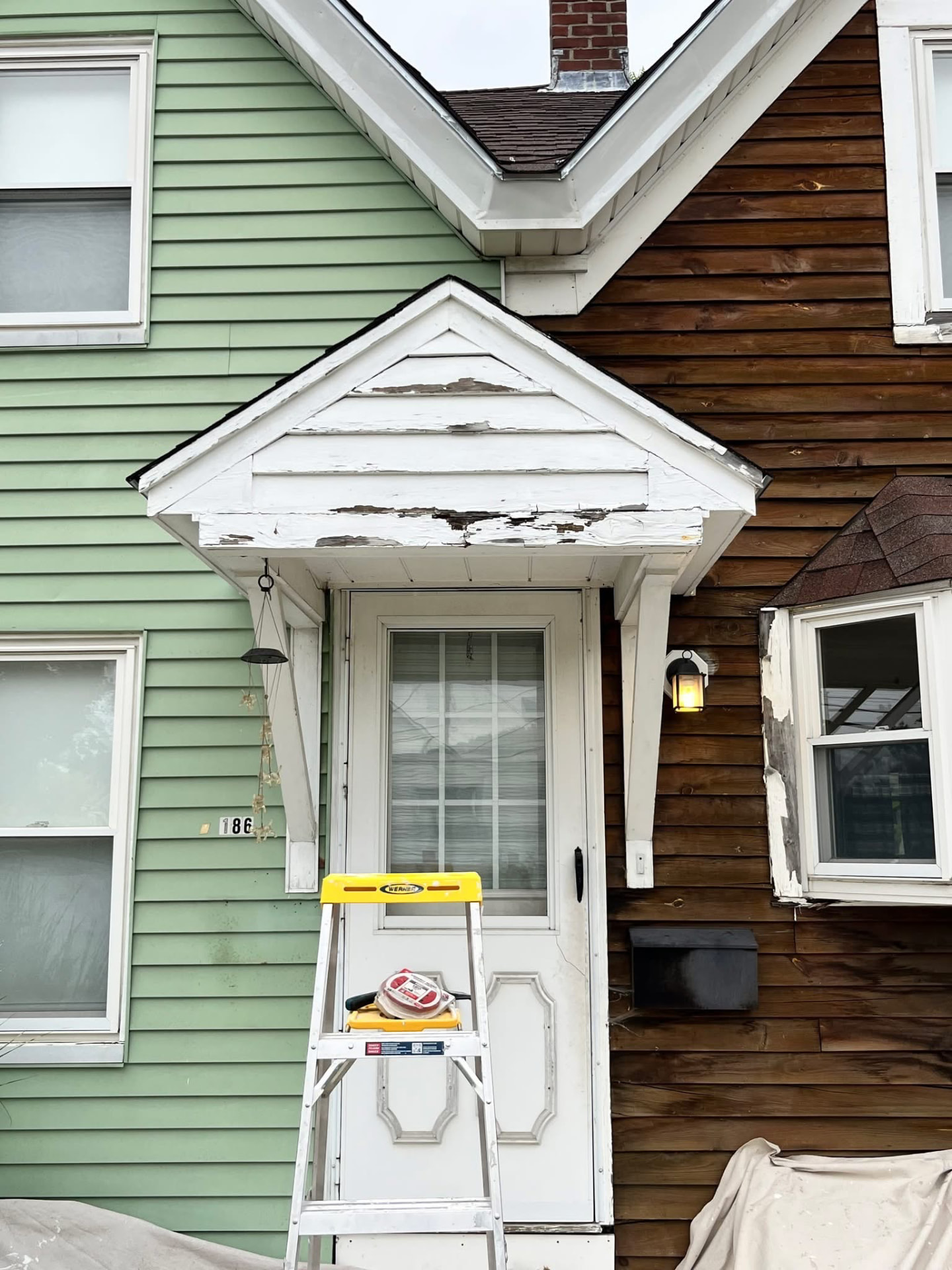 Front entry portico with heavily peeling white paint and bare weathered wood before restoration