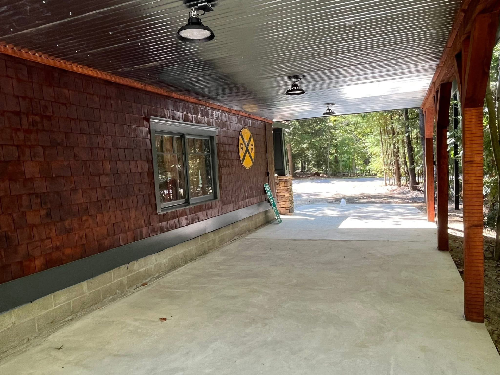 Covered breezeway with stained cedar shingles, dark green trim, and stained timber posts
