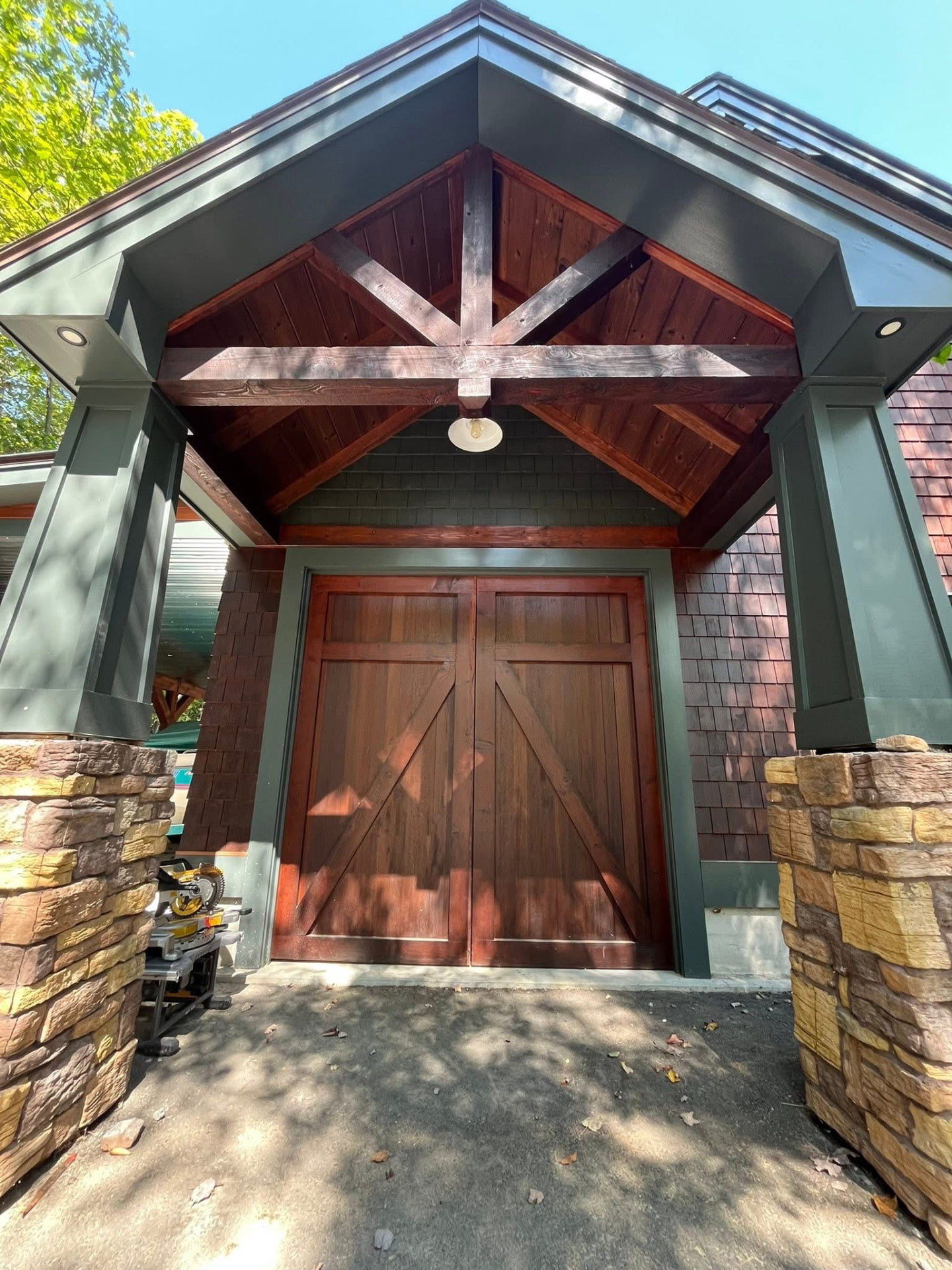 Timber-frame entry portico with stained cedar beams, dark green trim, and custom wood doors finished by TD Painting & Restoration